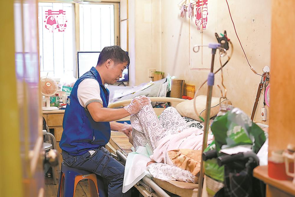长护险护理员郭立雄为重度失能老人按摩。